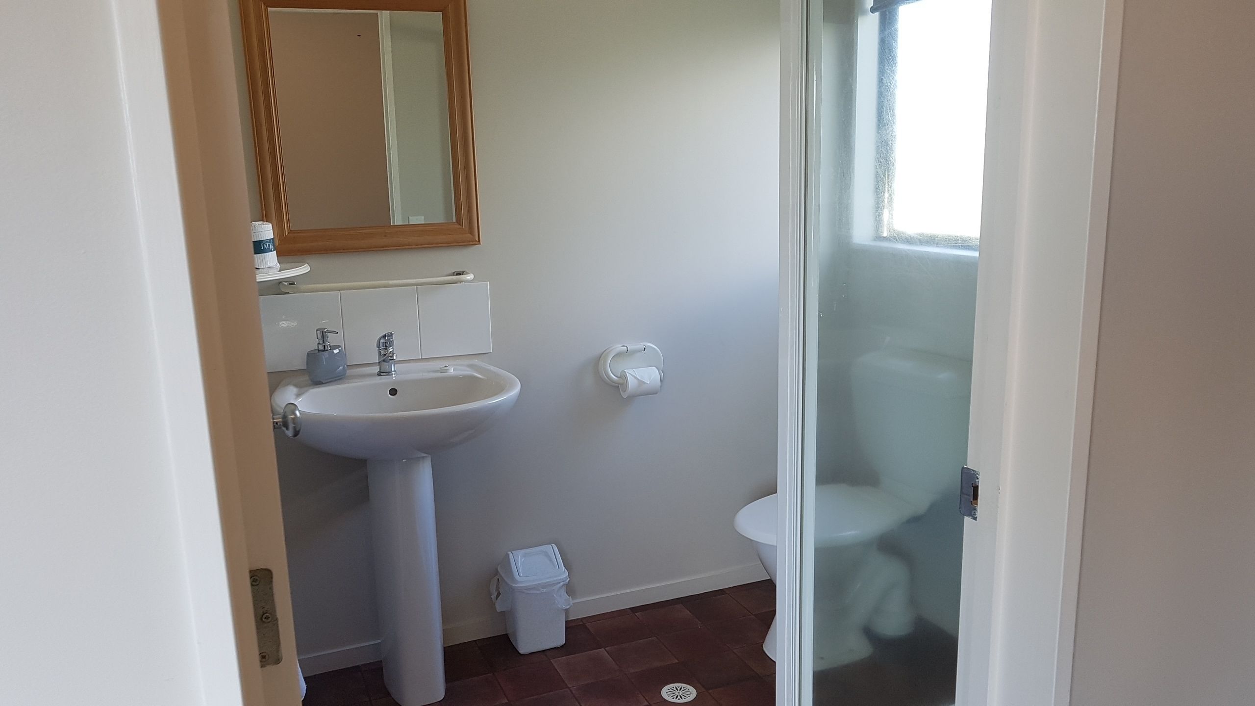 Een badkamer met een witte wastafel, spiegel en toilet.