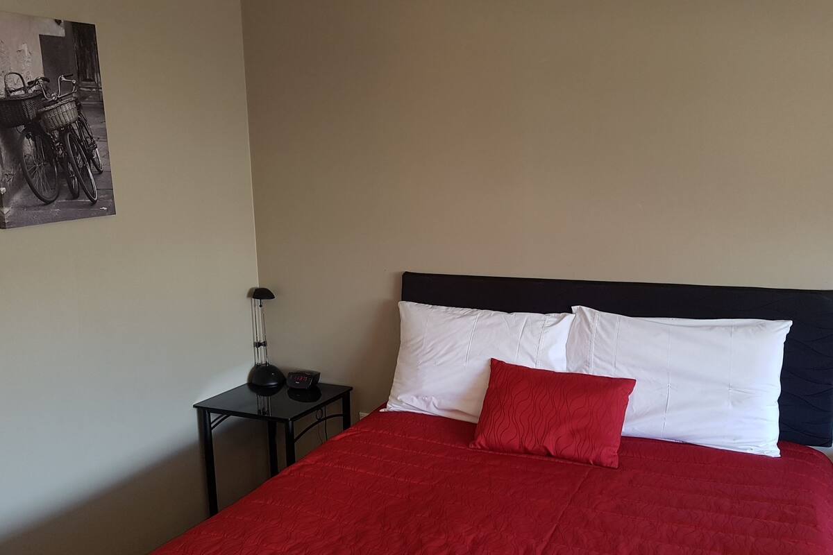 A bed with a red bedspread, white pillows, and a black headboard.