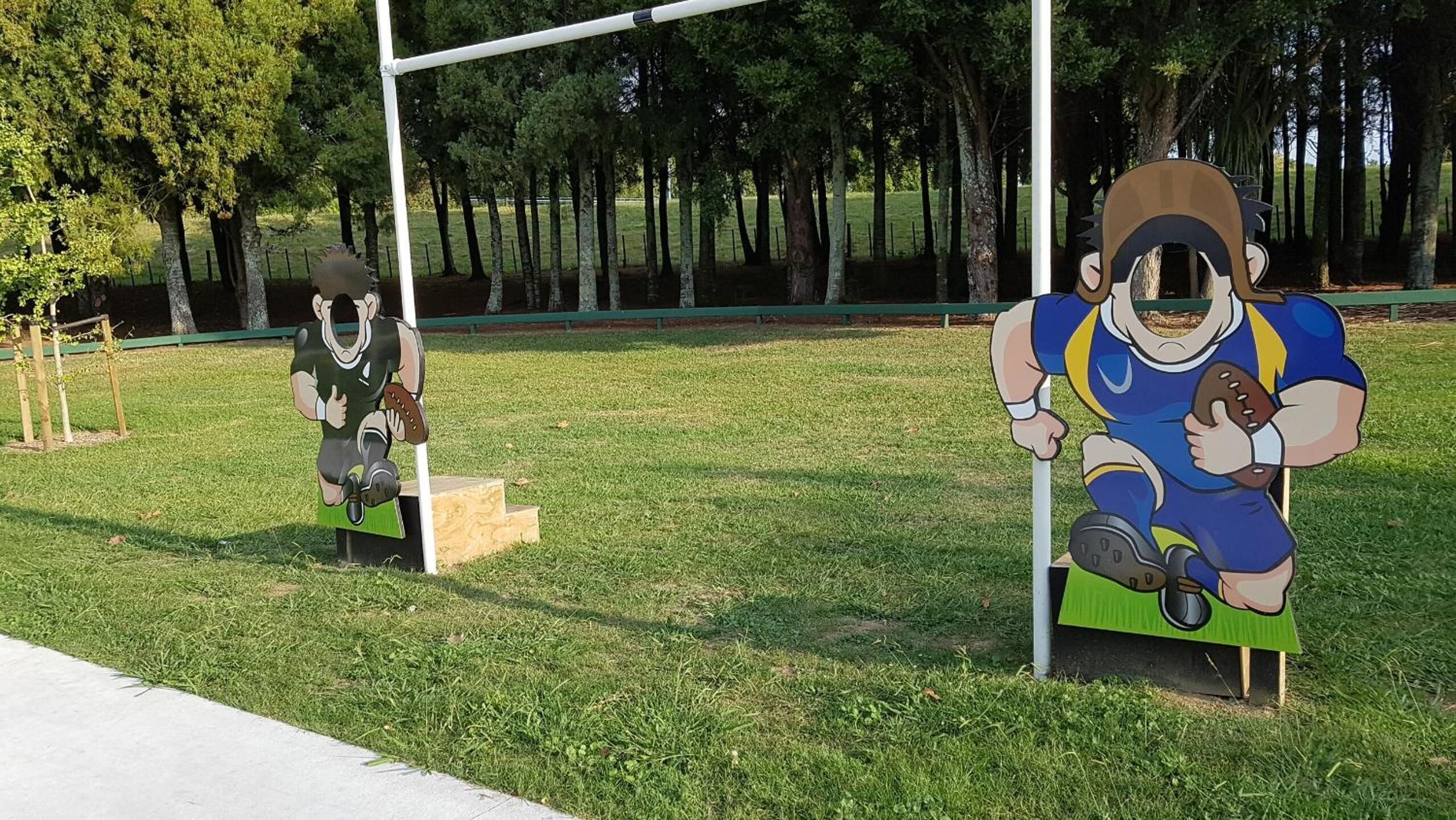 A park with two large, colorful sculptures of athletes on benches.