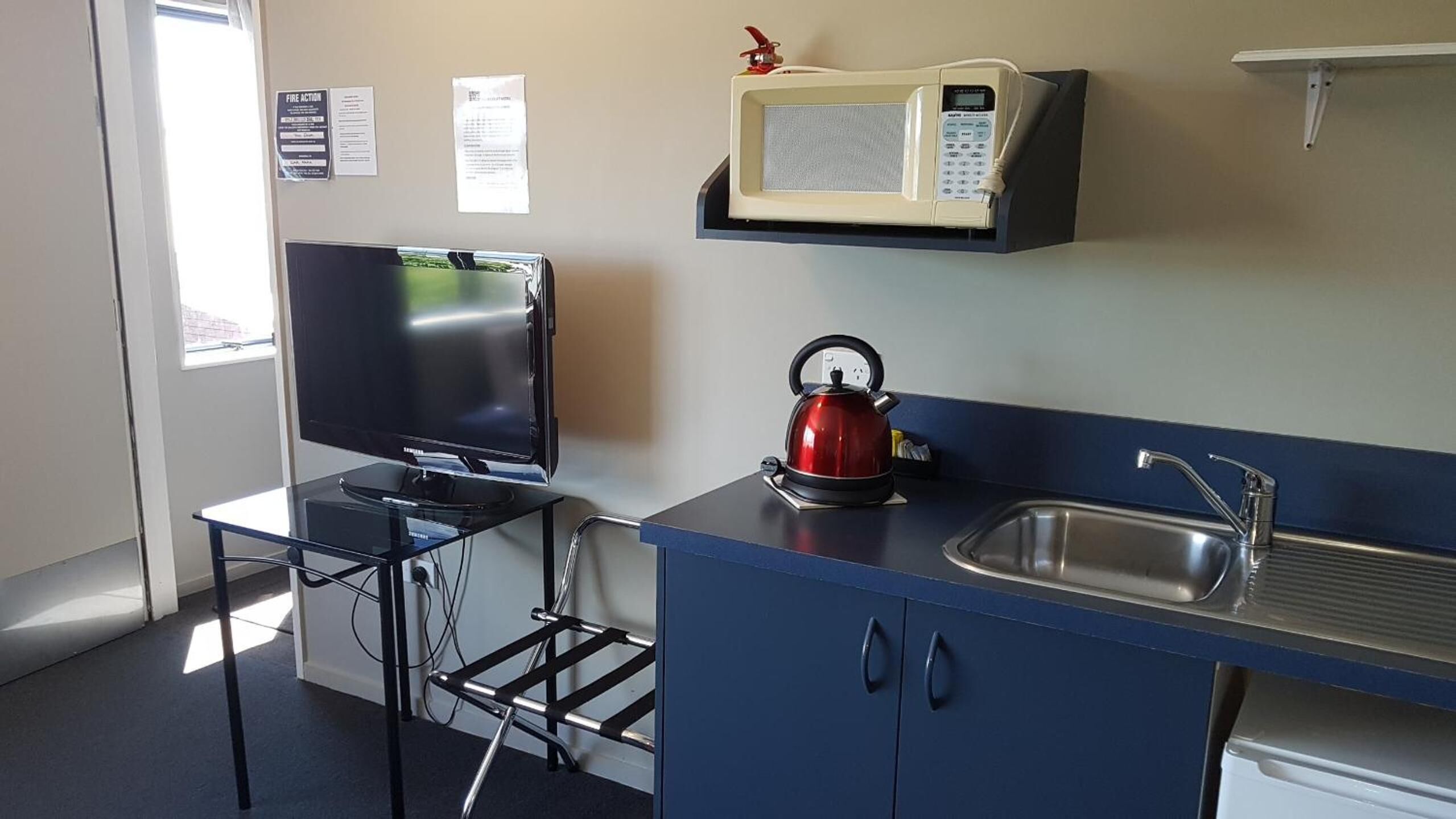 A compact kitchenette with a flat-screen TV, a kettle, a microwave, and a sink.