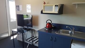 A compact kitchenette with a flat-screen TV, a kettle, a microwave, and a sink.