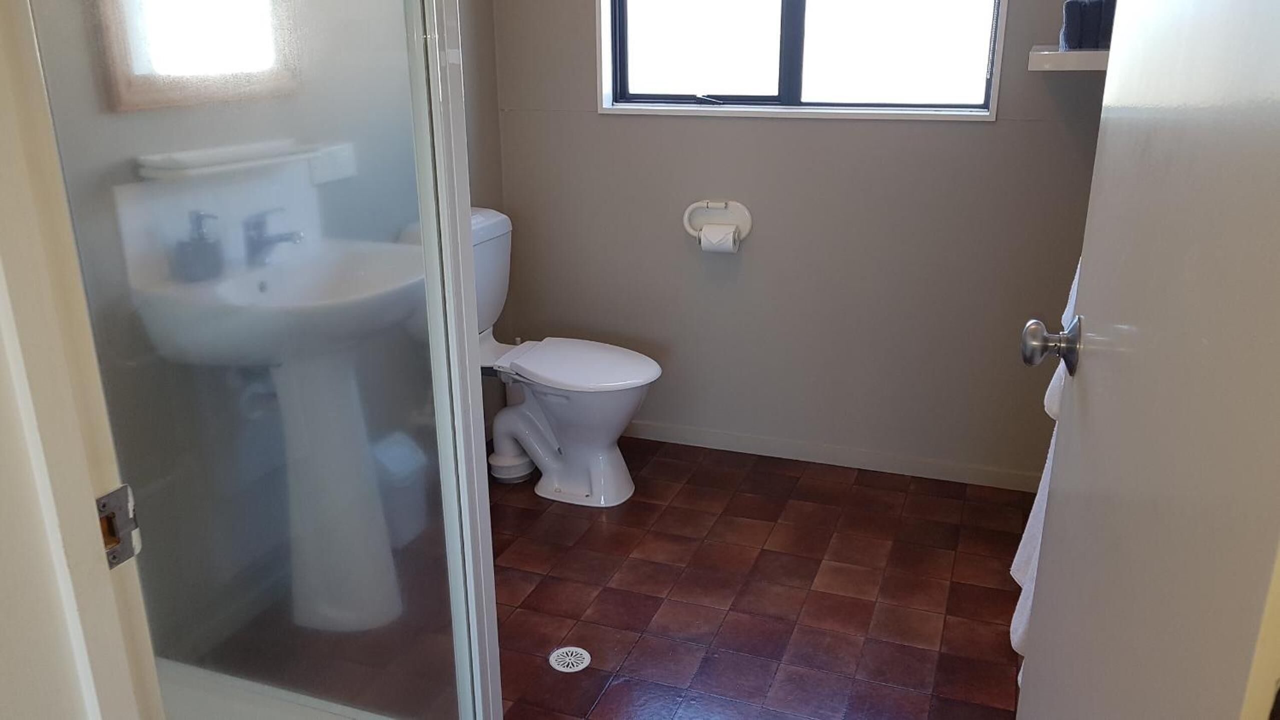 Un baño con inodoro, lavabo y ventana.
