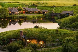 Un pueblo rural con casas de techo de paja, un estanque y un puente de piedra.