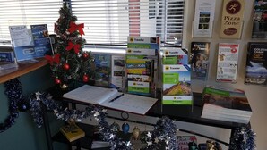 A desk with a Christmas tree, travel guides, and a laptop. - Palm Court Motel (Otorohanga)