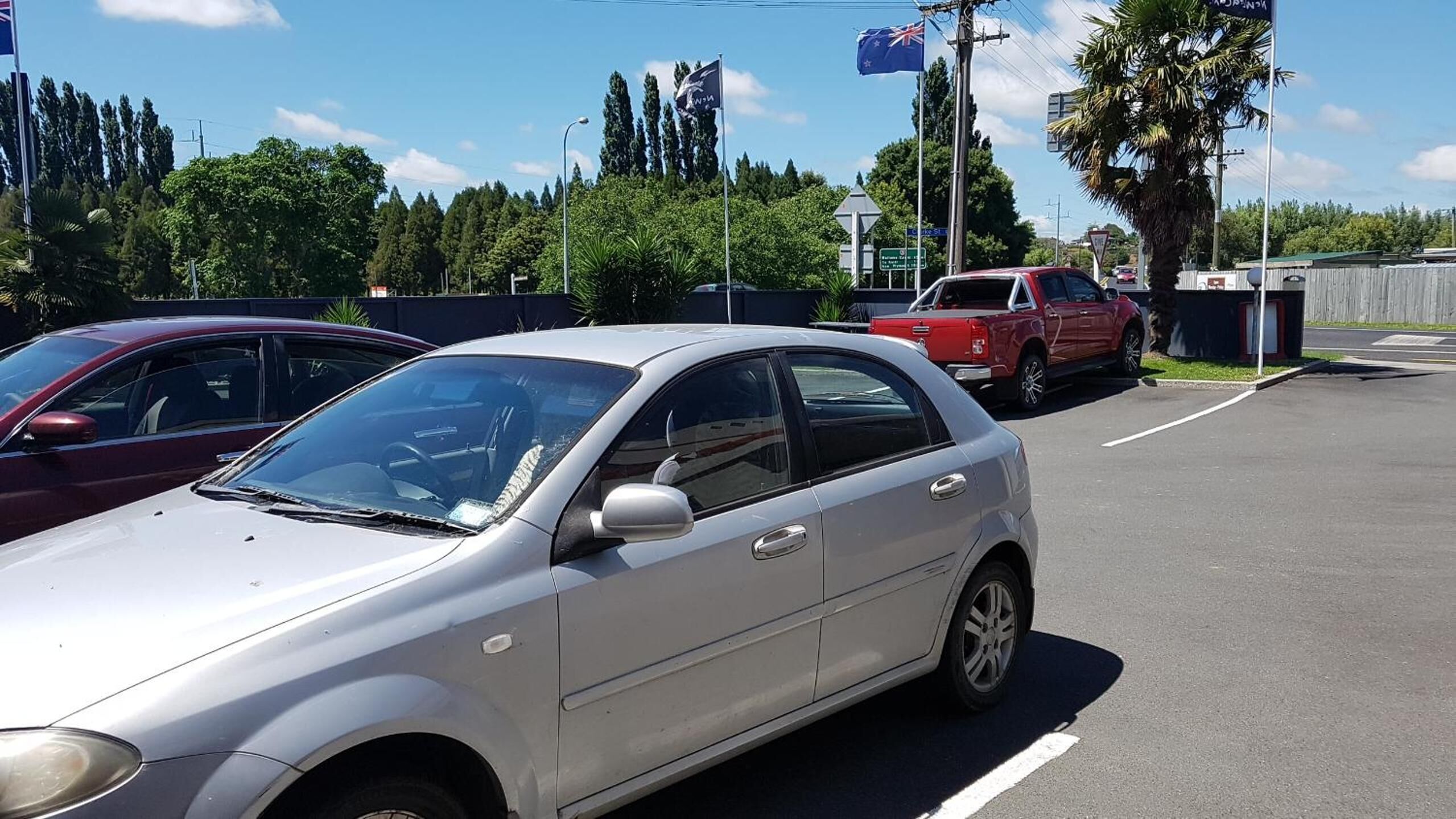 A parking lot with several cars, including a silver sedan and a red pickup truck.