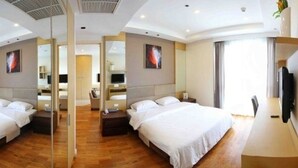 A hotel room with a large bed, a desk, a chair, and a TV.