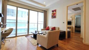 A modern living room with a sofa, coffee table, and a chair. There is a large window providing a view of the outside.