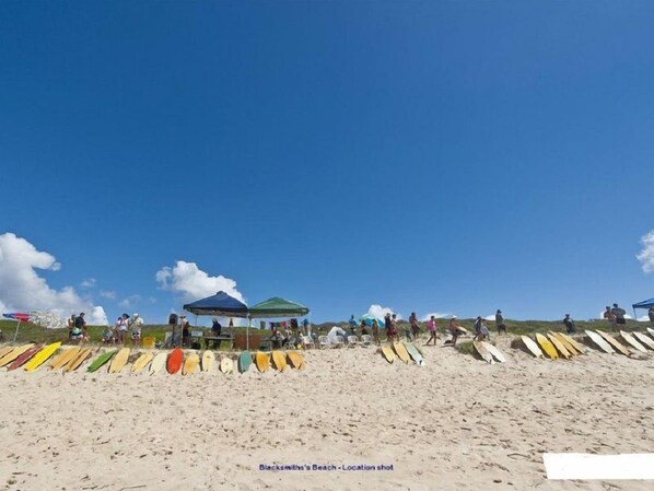 Ein Strand mit Menschen und farbenfrohen Surfbrettern, die dort liegen.