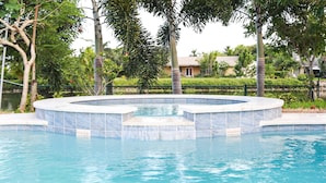 Ein Pool mit kreisförmigem Design, umgeben von Palmen und einem Zaun.