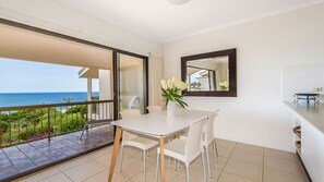 A modern room with a balcony, a dining table, and a view of the ocean. - Whale season is upon us, watch from your balcony (SUNSHINE BEACH)