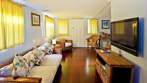 A living room with a sofa, armchairs, a TV, and a wooden TV stand. - Two Bedroom House Wooli (Wooli)