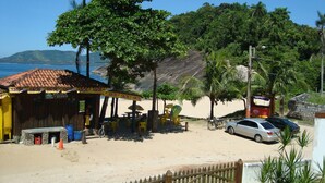A beachside café with outdoor seating, a stone wall, and a view of the beach and ocean.