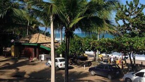A coastal area with palm trees, a beach, and parked cars.