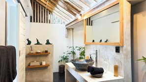 Een moderne badkamer met een grote spiegel, een stenen wastafel en planken met toiletartikelen.