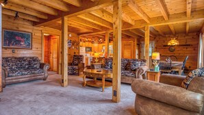 Interior d'una cabana de fusta amb saló, cuina i menjador.