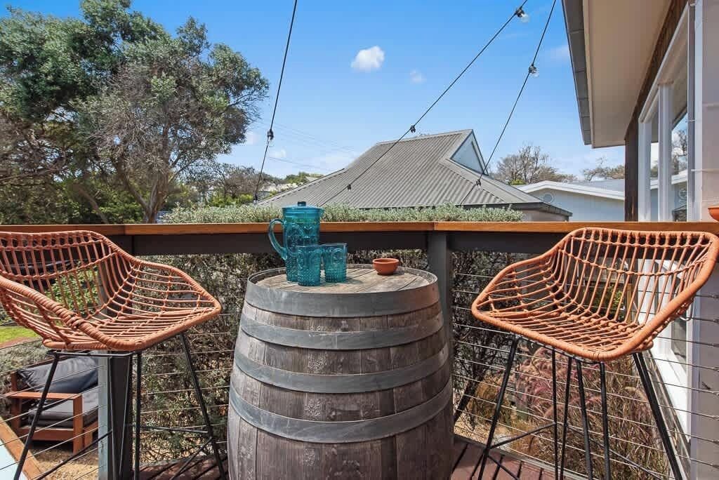A balcony with two wicker chairs, a wooden barrel, and a blue pitcher.