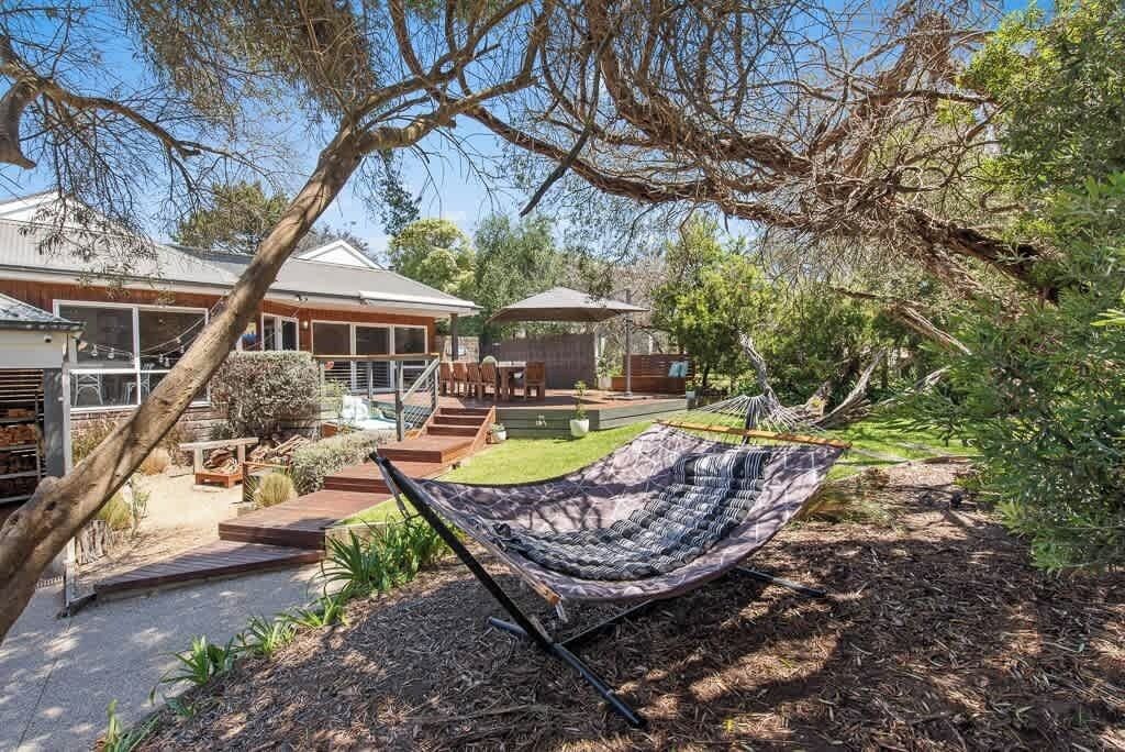 A hammock in a backyard with a house in the background.