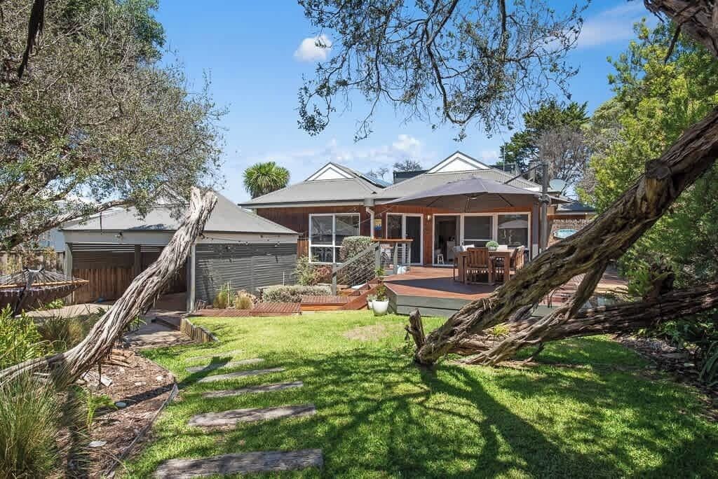 A residential property with a covered patio, a garage, and a landscaped backyard with a stone pathway.