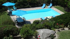 Una piscina rectangular con sillones de descanso y sombrillas.
