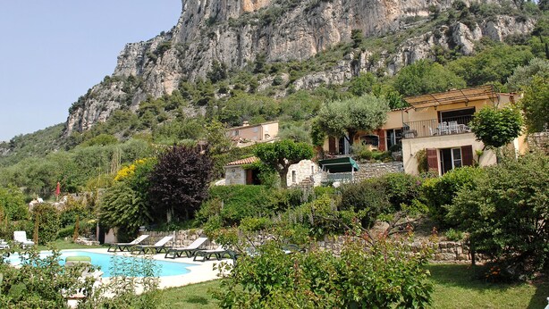 Una villa con piscina, rodeada de exuberante vegetación y montañas al fondo.