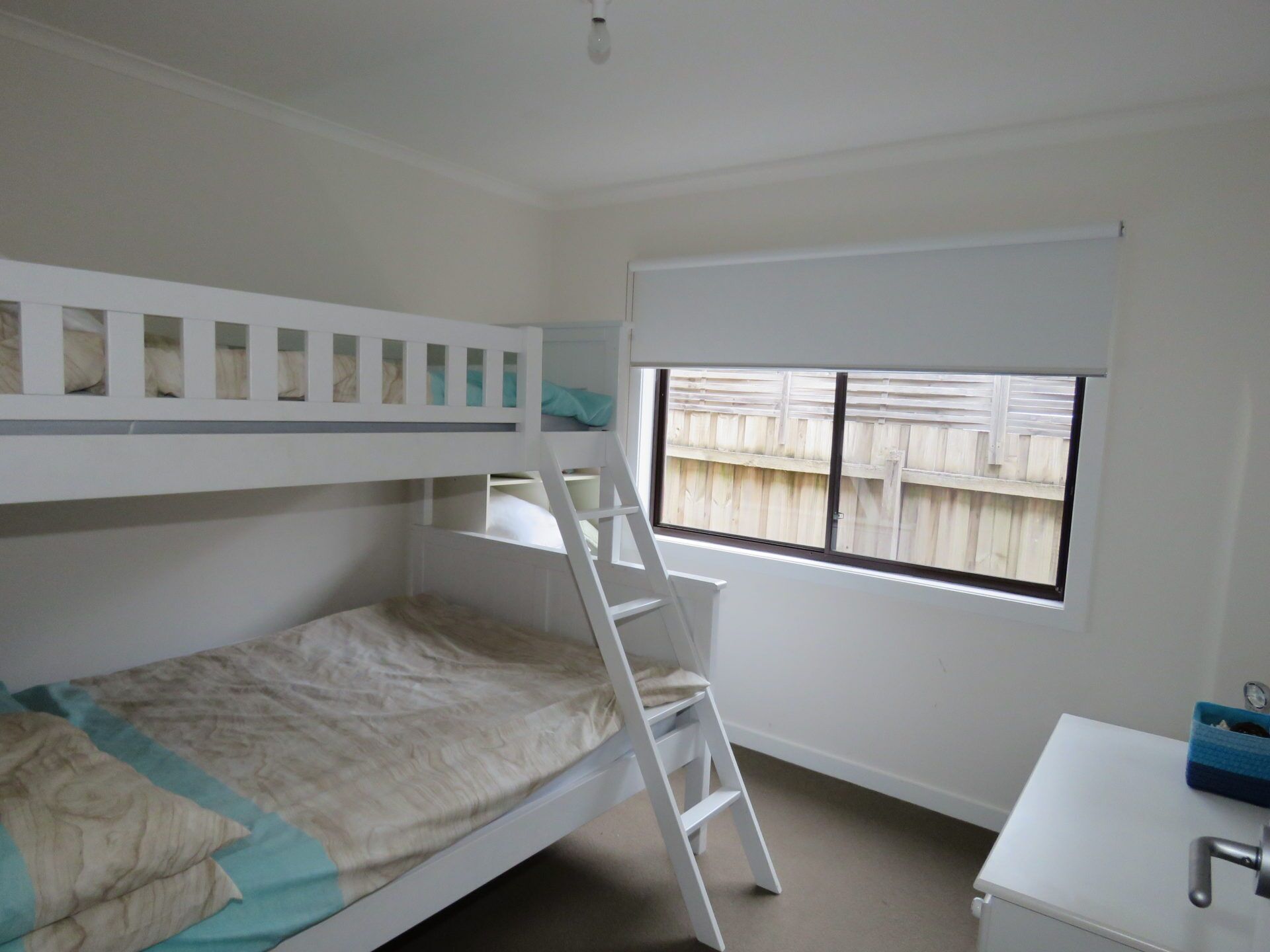 A bunk bed room with a window, a desk, and a ladder.