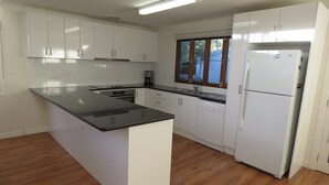 A modern kitchen with white cabinets, a black countertop island, and a built-in dishwasher. - Genesta Street, sleeps 14 people, in the heart of Cowes (Cowes)