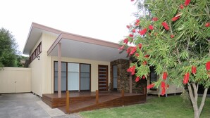 A modern house with a covered porch, a stone wall, and a tree with red flowers. - Genesta Street, sleeps 14 people, in the heart of Cowes (Cowes)