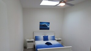 A bedroom with a white bed, blue bedding, a ceiling fan, and a nightstand with a lamp. - Genesta Street, sleeps 14 people, in the heart of Cowes (Cowes)
