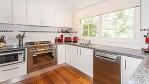A modern kitchen with stainless steel appliances, white cabinetry, and a large window providing natural light.