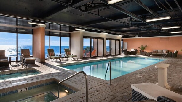 A pool area with a view of the ocean, lounge chairs, and a hot tub. - Panoramic Views from spacious 3 BR 2 BA condo (Myrtle Beach)