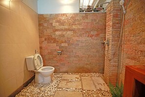 Bathroom features a toilet, shower area with metal hose, and a unique tile design.