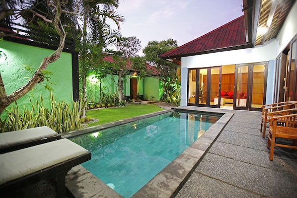 Relax by the serene pool surrounded by lush greenery and a well-maintained lawn.