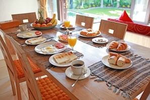 Enjoy a leisurely breakfast in a cozy room with a garden view, featuring a table set for four with a variety of breakfast items.