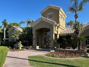 Stunning two-story residence with a central entrance, flanked by windows, set amidst beautifully maintained gardens and palm trees.