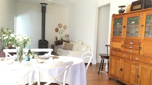 A dining area with a white table and chairs, a wooden cabinet with glass doors, and a white sofa in the background.