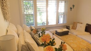 A hotel room with a bed, a bedside table, a lamp, and a window with blinds.