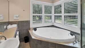 A bathroom with a large bathtub, two sinks, and a window with blinds. - "School House Villa" hosted by Halls Gap Accommodation (Halls Gap)