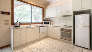 A modern kitchen with white cabinets, a stainless steel oven, a microwave, and a refrigerator. - "School House Villa" hosted by Halls Gap Accommodation (Halls Gap)