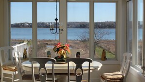 A dining area with a table and chairs, a chandelier, and a view of a lake. -  Luxury Waterfront Home with Pool and Dock  NEW 5% Discount Until Feb. 28th (eastham)