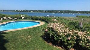 A swimming pool with lounge chairs, a garden with pink flowers, and a view of the lake with sailboats. -  Luxury Waterfront Home with Pool and Dock  NEW 5% Discount Until Feb. 28th (eastham)