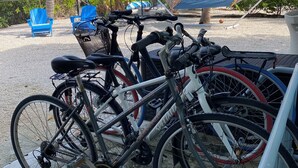 Des vélos sont garés sur une surface en béton, avec un hamac et des chaises bleues en arrière-plan.
