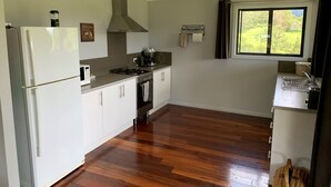 A modern kitchen with white cabinets, a stainless steel range, and a window with a view of greenery.