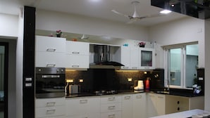 A modern kitchen with white cabinets, a black countertop, and a ceiling fan.
