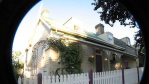 Een huis met een witte picket fence, een groen dak en een schoorsteen.