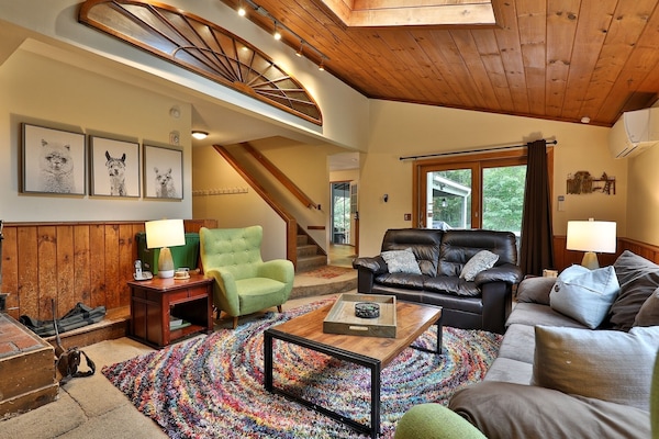 Main living room with high ceilings, fireplace, and open gathering space.