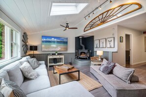 Een gezellige woonkamer met een open haard, twee banken, een salontafel en een groot raam.