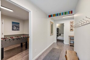 A hallway with a foosball table, a mirror, and a bed in the background.