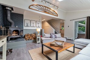 A cozy living room with a fireplace, a sofa, a coffee table, and a staircase leading to an upper level.