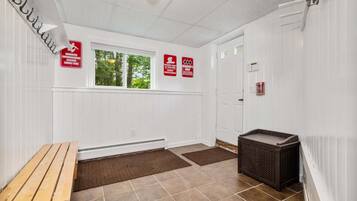Une pièce avec un banc, une poubelle et une porte. Des panneaux sont affichés sur le mur, indiquant les règles à respecter dans cet espace.