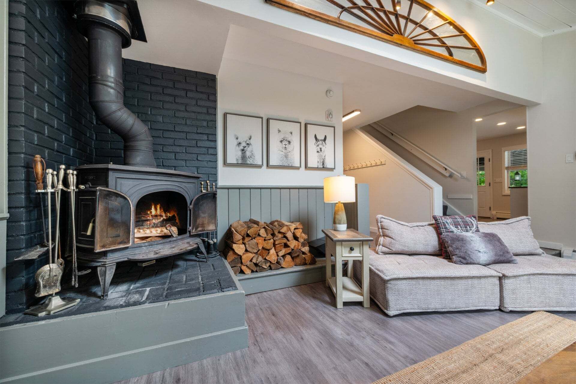 A cozy living room with a fireplace, a sofa, and a staircase.